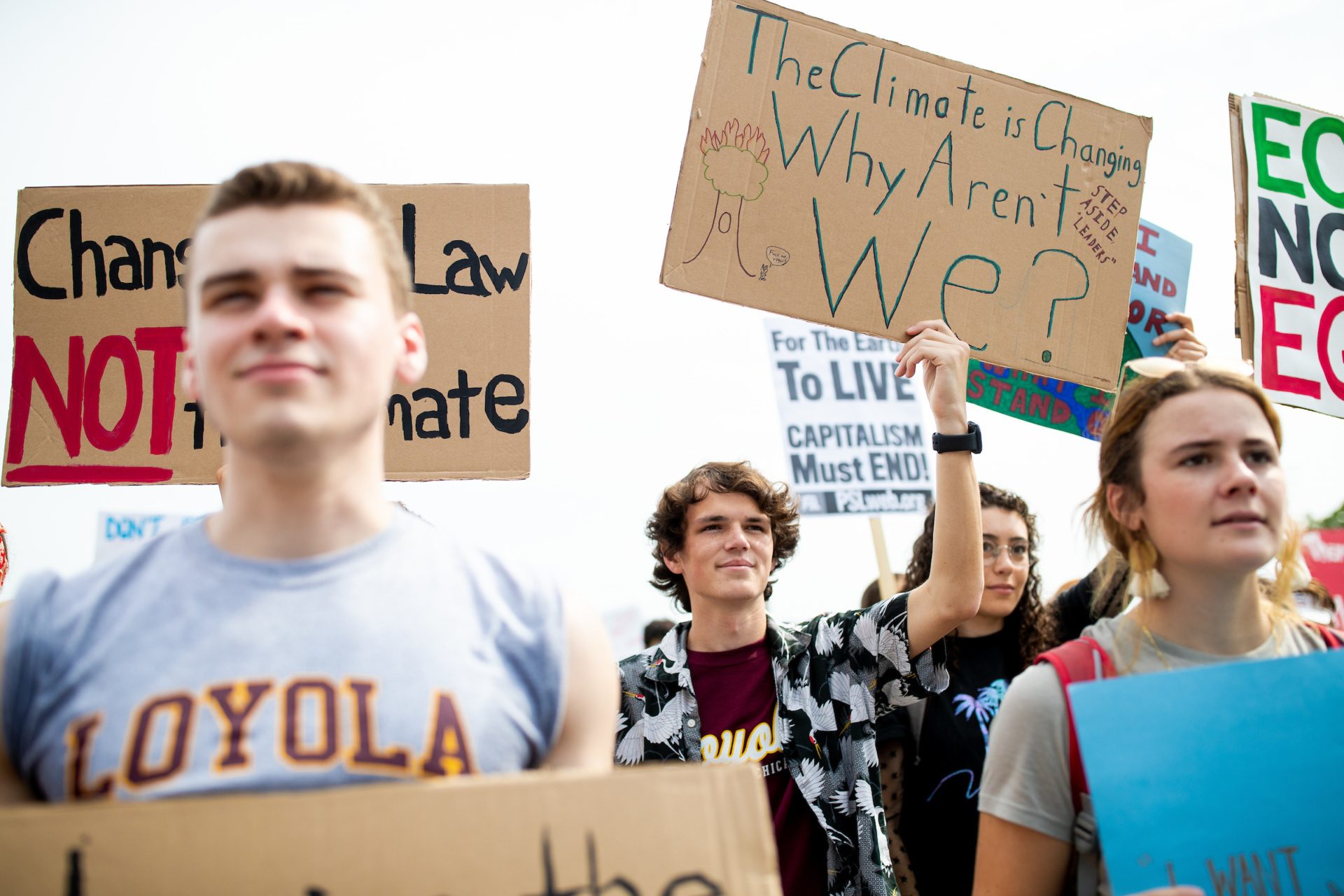 A group of Loyola University Chicago students hold protest signs. One sign reads 