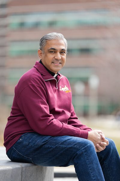 A portrait of Ternan Monteiro, SJ, smiling outdoors on Loyola University Chicago's campus
