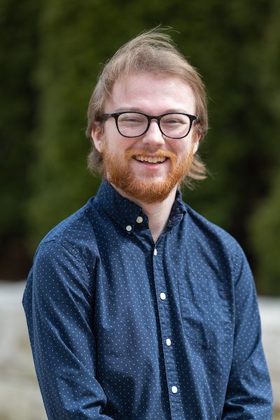 A portrait of John Gorman smiling outdoors on Loyola University Chicago's campus