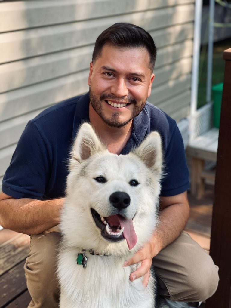 A portrait of Alfredo Arreola Pérez smiling with a white, fluffy dog