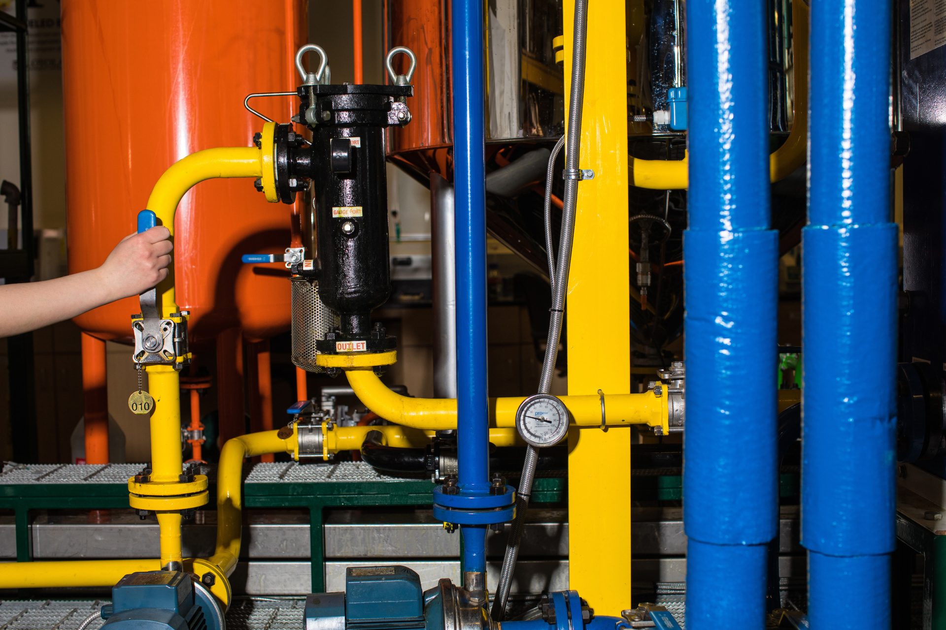 Turning on a valve to begin the flow of cooking grease through a filter before it continues on the in biodiesel production process.