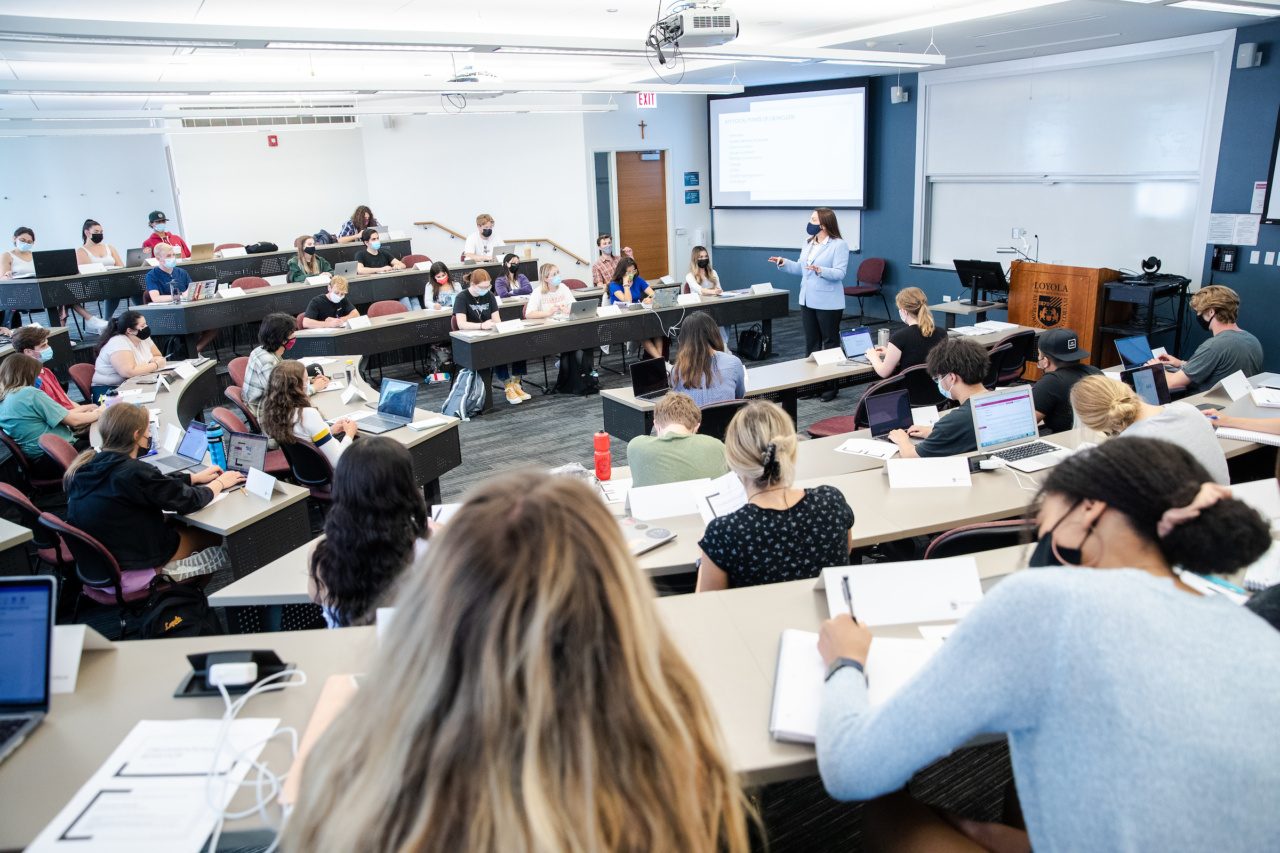 Professor standing in front of whiteboard teaching students in classroom
