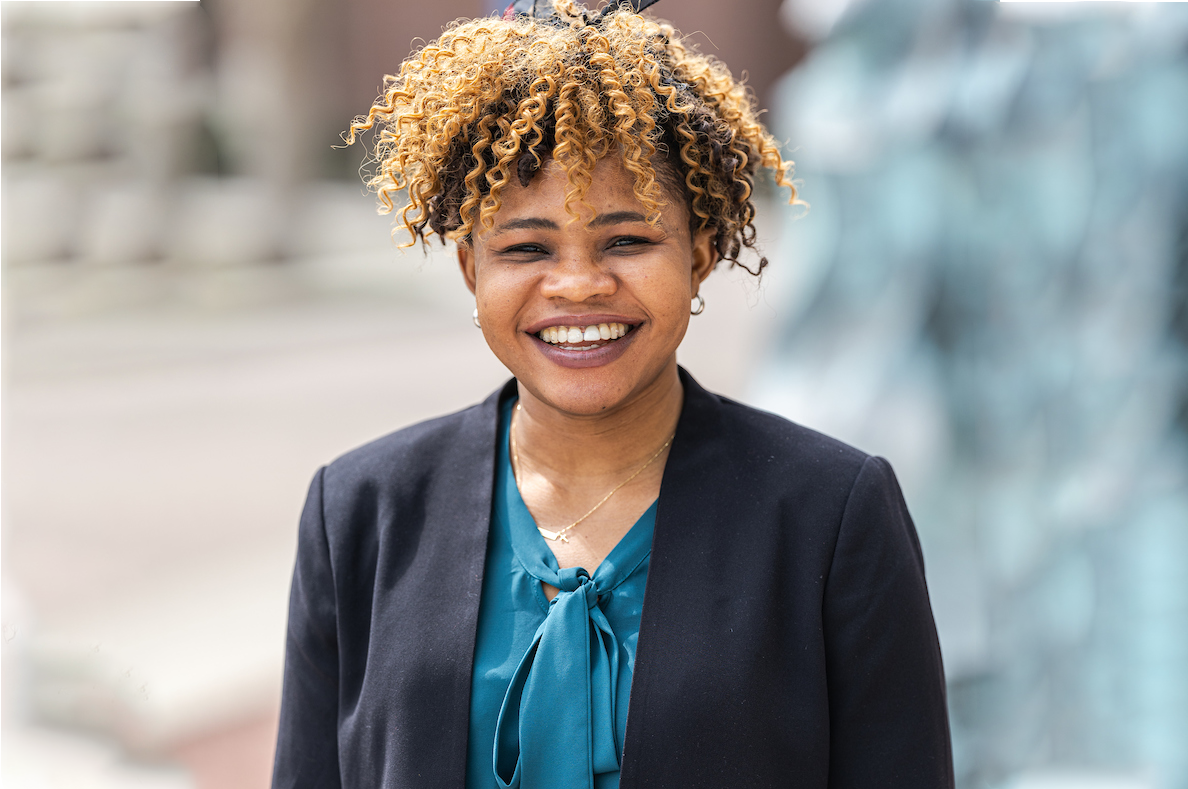 Student in blazer smiling in front of statue of Loyola's Lakeshore Campus