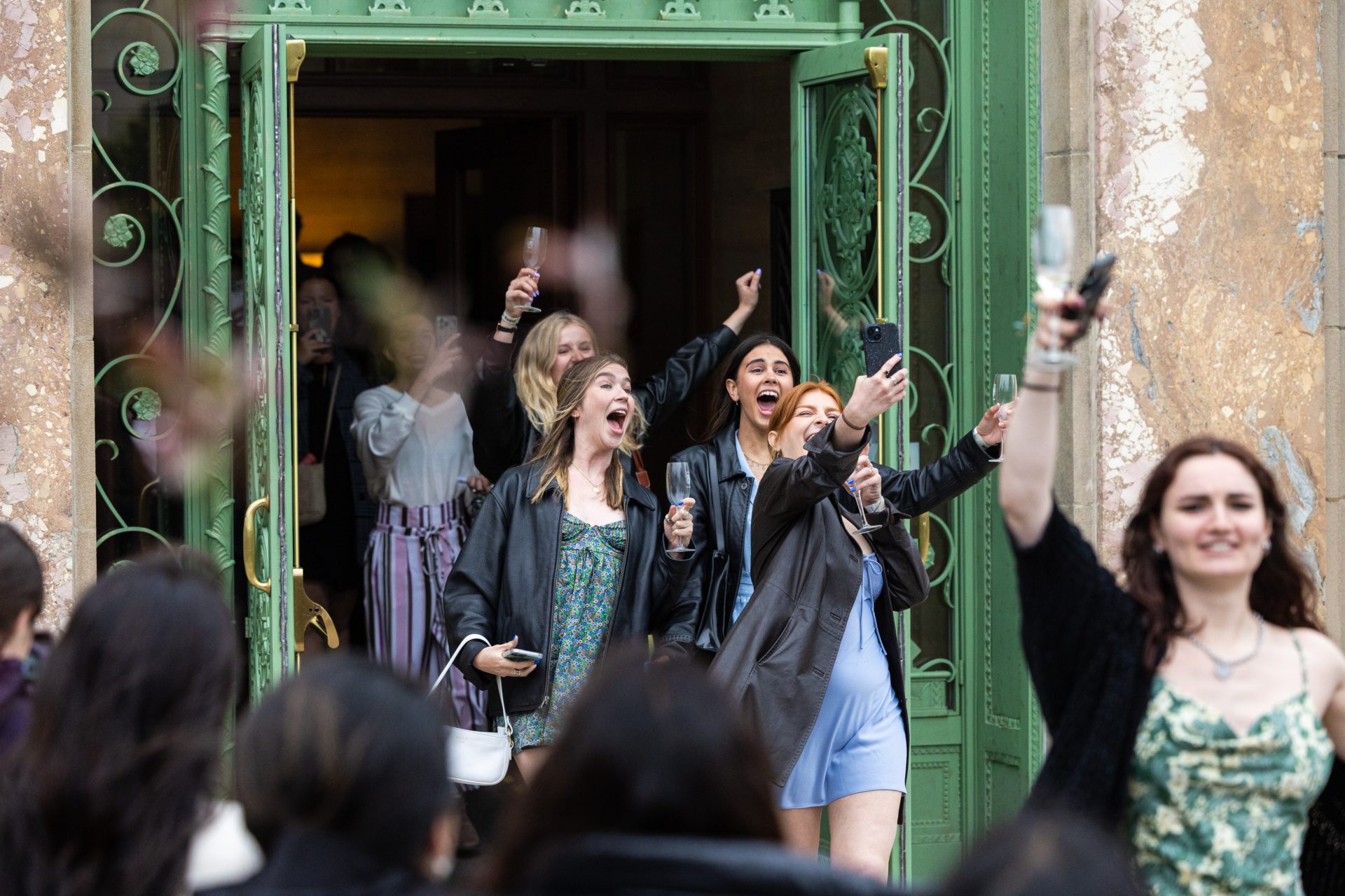 Loyola University Chicago students take selfies and cheer as they walk through a set of green doors